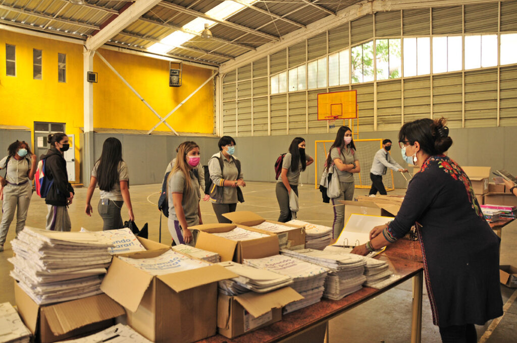 Docentes entregando textos escolares a las familias en el hall del colegio